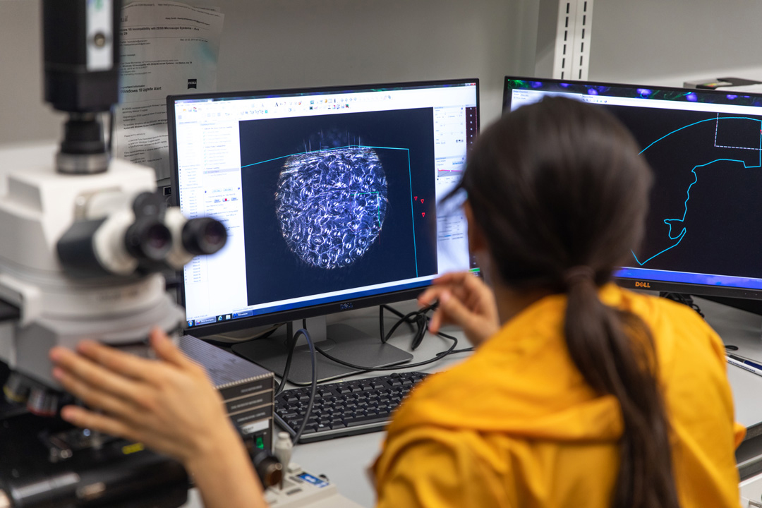 Student working with a microscope and computer