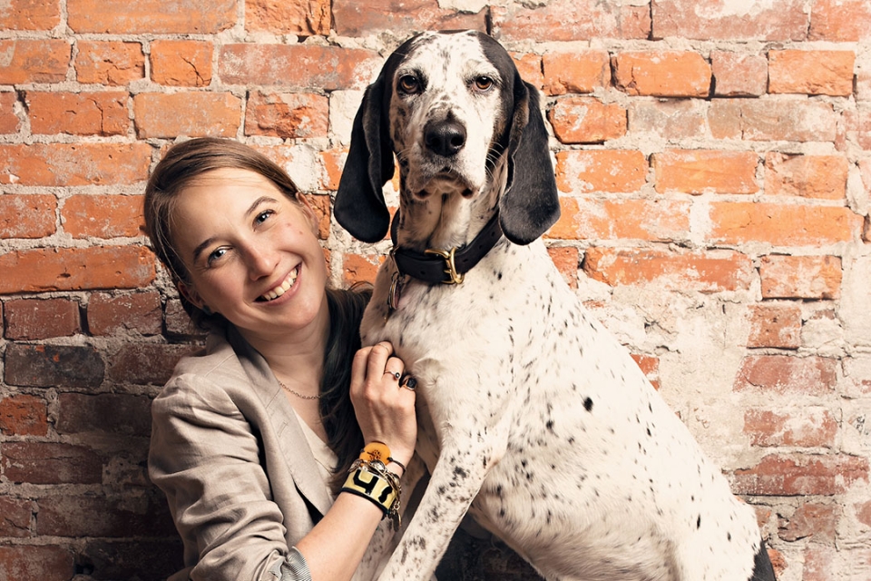Courtney Sexton smiling with her large black and white hound on her lap